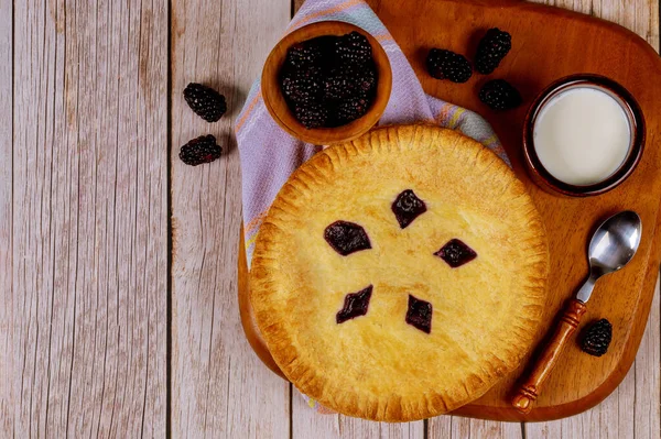 Homemade blackberry pie with fresh blackberries and milk.