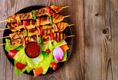 Ahşap şişte ızgara tavuk kebabı ve acı sos..
