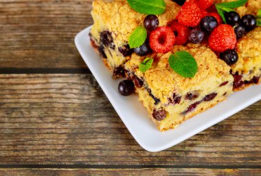 Ahşap arka planda taze böğürtlenli yaban mersinli turta.