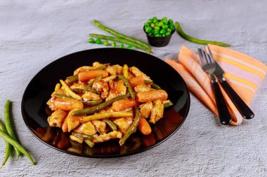 Tavuklu teriyaki, siyah tabakta çatal ve bıçaklı sebze..