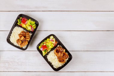 Beyaz ahşap yüzeyinde lezzetli yiyecekler olan iki plastik kap..