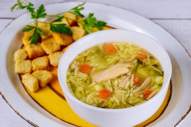 Tavuklu erişte çorbası, maydanoz, sebze ve kızarmış ekmek..