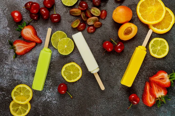 Homemade orange, coconut and lime popsicles on dark background. Top view.