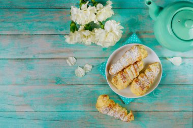 Vanilyalı tatlı pasta külahı ve ahşap masada çaydanlık..