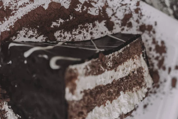 A piece of dark chocolate cake with two cream layers — Stock Photo, Image