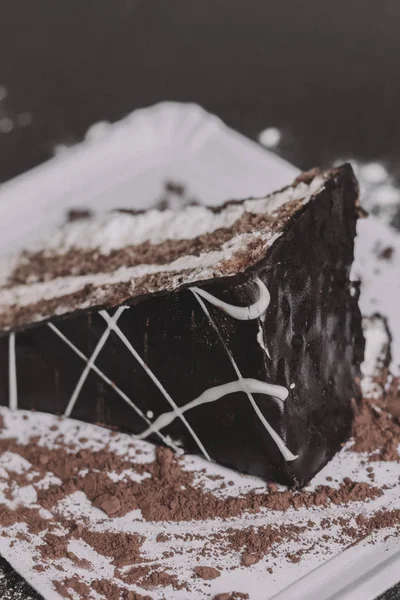 A piece of dark chocolate cake with two cream layers — Stock Photo, Image