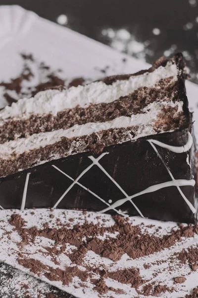 A piece of dark chocolate cake with two cream layers — Stock Photo, Image