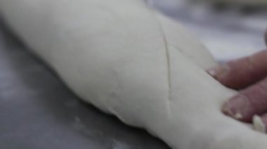 Şef masada hamur ekmeği kesiyor.