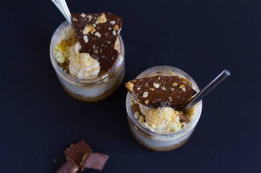 Siyah zemin üzerinde çikolata ve badem parçaları olan iki parça beyaz krema. Genel Bakış