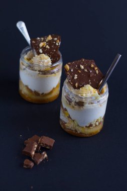 Siyah zemin üzerinde çikolata ve badem parçaları olan iki parça beyaz krema.