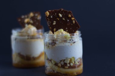 Siyah zemin üzerinde çikolata ve badem parçaları olan iki parça beyaz krema.