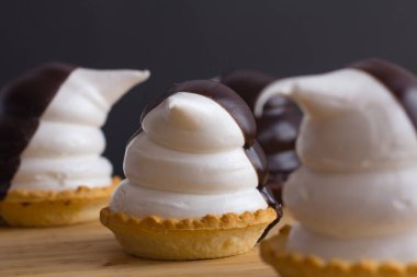 Komik penguen şeklinde kapkekler. Siyah arka planda çikolata ve ahşap kaplama.