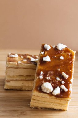 İki parça krema ve pandispanya, kahverengi arka planlı ahşap parçaların üzerine.