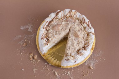 Kahverengi zemin üzerinde kurabiye parçaları olan beyaz kremalı pasta. Tam görünüm
