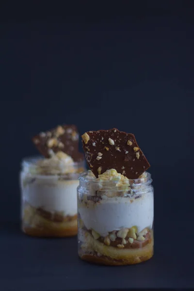 Two pieces of white cream with chocolate and almond pieces layers on black background
