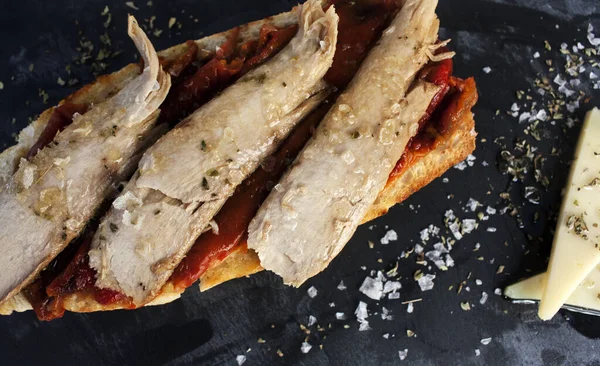 Kırmızı biberli tost ekmeği, bonfile ve siyah arkaplanda iki dilim peynir.