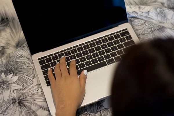 Young hands typing on the laptop. Working concept at the bed