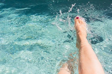 Havuzda su sıçratan güzel kadın bacakları.