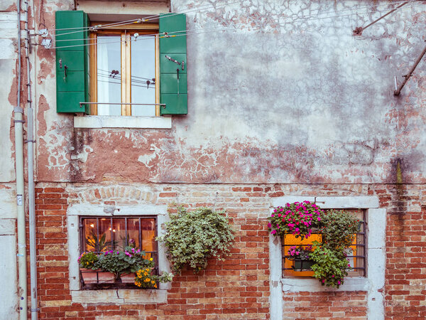 Picturesque windows with shutters and flowers in Venice, Italy