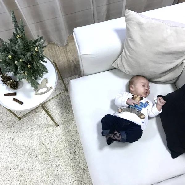 Bebek Noel 'de beyaz bir kanepede uzanıyor ve tatlı tatlı uyuyor.