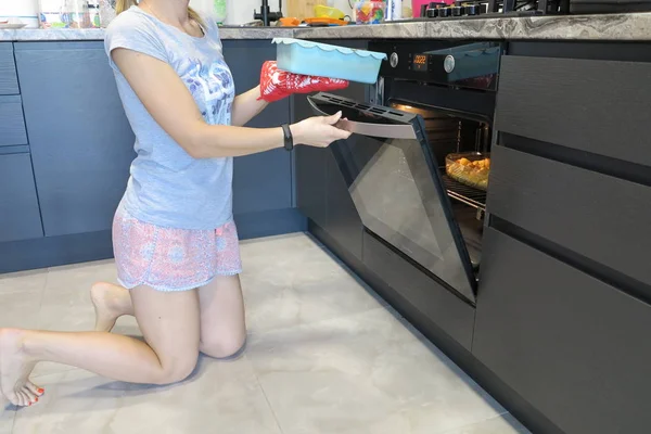 Pembe şortlu bir kız, fırın turtasından siyah cepheli bir mutfak pastası alıyor.