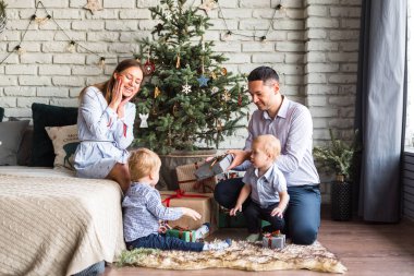 Aile (anne, baba, iki oğul) süslü Noel ağacının yanındaki halıya oturur ve eğlenir, bayramı beklerler. Mutlu aile, birbirlerine hediye verirler.