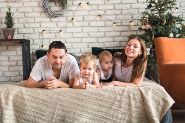 Mutlu Avrupalı bir aile kanepeye uzanıp birlikte vakit geçiriyor, aile mutlu. Anne, baba, oğul, iki oğul, gülümseyen ve eğlenen, çılgınca eğlenen. Aileyle vakit geçirmek. Hepsi beyaz tişört ve kot pantolon giymiş, rahat giyimli.