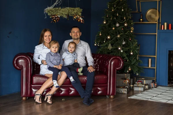 Aile (anne, baba, iki oğul) süslü Noel ağacının yanındaki kanepede oturur ve Noel 'i beklerken eğlenir. Mutlu gülümseme ailesi