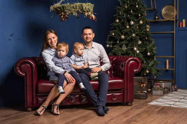 Aile (anne, baba, iki oğul) süslü Noel ağacının yanındaki kanepede oturur ve Noel 'i beklerken eğlenir. Mutlu gülümseme ailesi