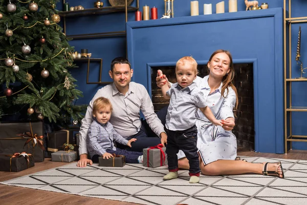 Aile (anne, baba, iki oğul) süslü Noel ağacının yanındaki halıya oturur ve eğlenir, bayramı beklerler. Mutlu aile, birbirlerine hediye verirler.