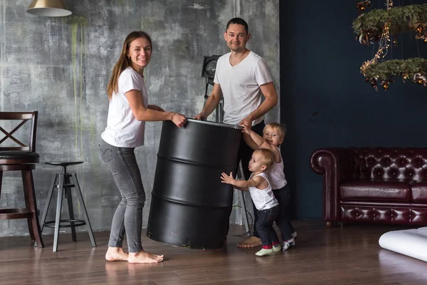 happy European family dragging a barrel children help parents family happy. mother, son, two sons, smiling and messing around, madly having fun. Spending time with family. all dressed in white t-shirts and jeans, comfortable clothing style
