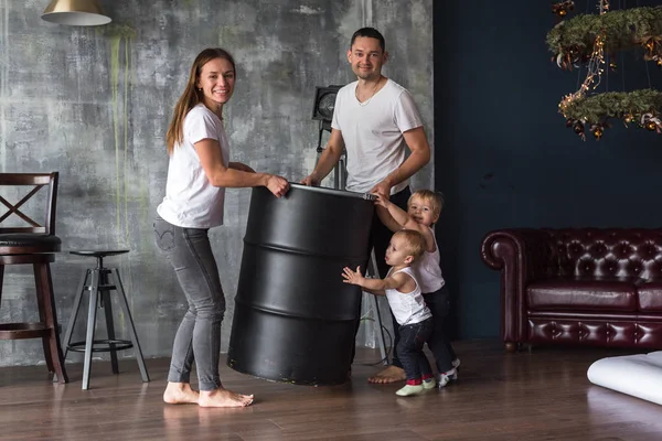 Fıçı çocuk taşıyan mutlu Avrupalı aile ebeveynlerin mutlu olmasına yardım eder. Anne, oğul, iki oğul, gülümseyen ve oyalanan, çılgınca eğlenen. Aileyle vakit geçirmek. Hepsi beyaz tişört ve kot pantolon giymiş, rahat giyimli.