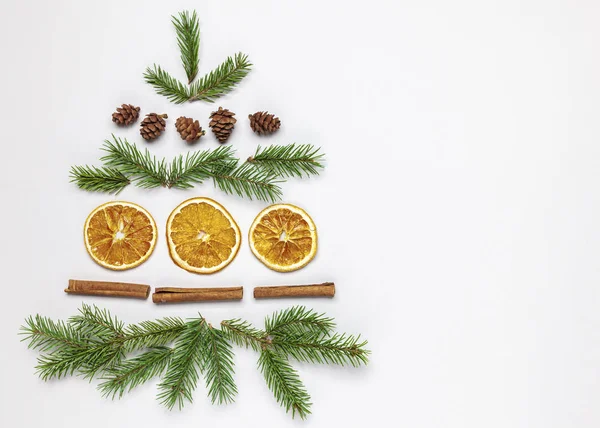 Ladin dallarından, kozalaklardan, kurutulmuş portakallardan ve tarçın çubuklarından yapılmış Noel ağacı. Beyaz arka planda Noel kompozisyonu. Üst görünüm, alanı kopyala