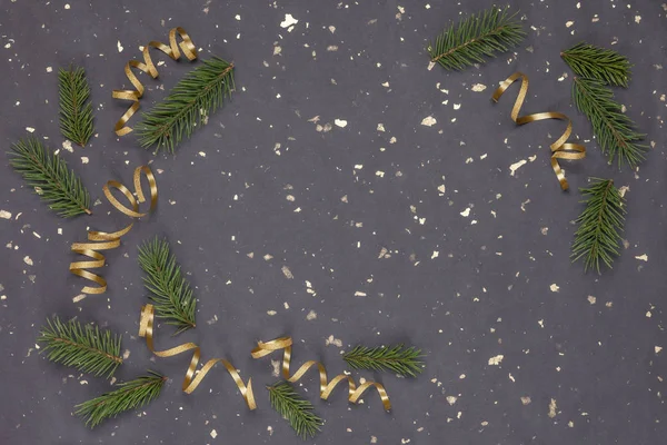 Ladin dalları ve altın kurdelelerden yapılmış bir Noel çerçevesi. Koyu kağıt arka plan. Yeni yıl. Üst görünüm