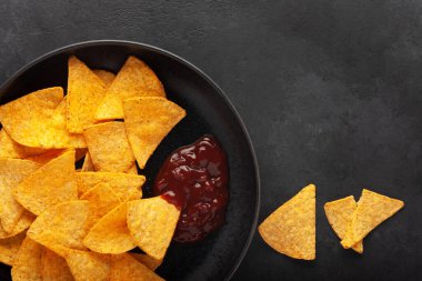 Siyah tabakta soslu cips. Karanlık arka plan. Üst Manzara. Boşluğu kopyala.