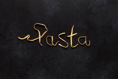Siyah arkaplanda Tagliatelle 'den yapılmış kelime makarnası.
