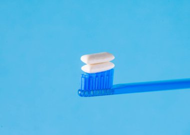 Taze nefes. Diş fırçasında diş macunu yerine sakız çiğnemek. Mavi arkaplan.