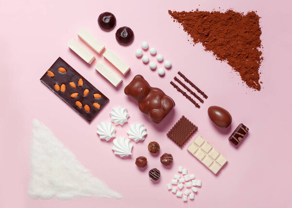 Sweet food. Knolling style. Composition made of a handful of sugar and cocoa, sweets, chocolate, marshmallows on a pink background