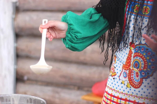 Ulusal elbiseli kız krep pişiriyor, seçici odaklanıyor.