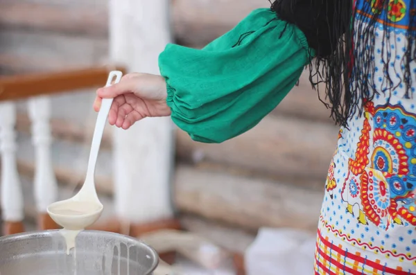 Ulusal elbiseli kız krep pişiriyor, seçici odaklanıyor.