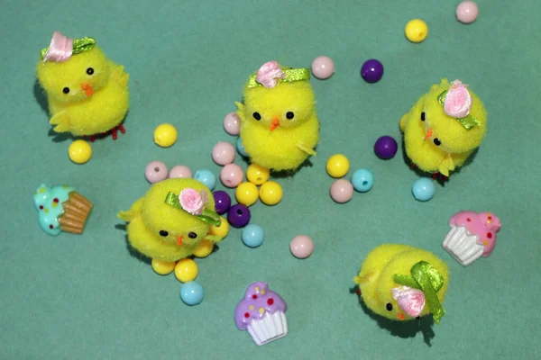 Yeşil arka planda boncuklu sarı oyuncak tavuklar.