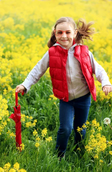 Kırmızı yelekli bir kız ve sarı çiçekli kırmızı bir şemsiye.