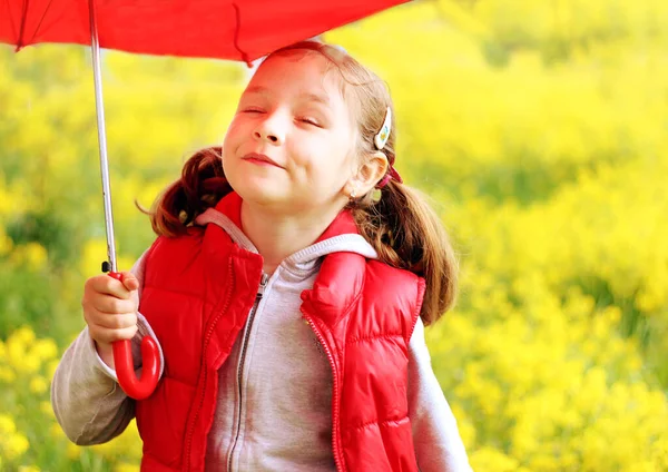 Kırmızı yelekli bir kız ve sarı çiçekli kırmızı bir şemsiye, parlak renkler