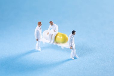 İki sıhhiyeci sedyede bir hap taşırken bir doktor üstte oturuyor.