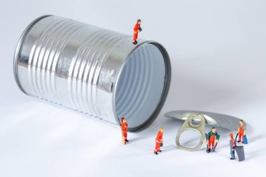 Minyatür İşçiler bir teneke kutuyu temizleyip geri dönüştürüyorlar