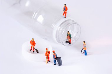 Minyatür İşçiler plastik bir şişeyi temizleyip geri dönüştürüyorlar.