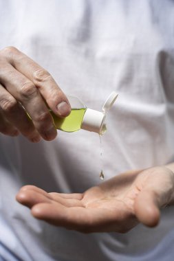 Erkek elleri antiseptik tutuyor. Bakteriden bir damla jöle ile el tedavisi. Kişisel izolasyon
