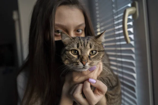 Uma Menina Com Uma Máscara Médica Preta Pela Janela Abraça — Fotografia de Stock