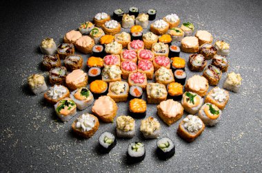 Büyük bir rulo ve suşi seti. Sostan şapka. Pişmiş ekmek. Gri arkaplan