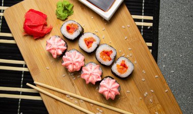 Tahta tahtada sebzeli vejetaryen dürümleri. Beyaz bardakta soya sosu.